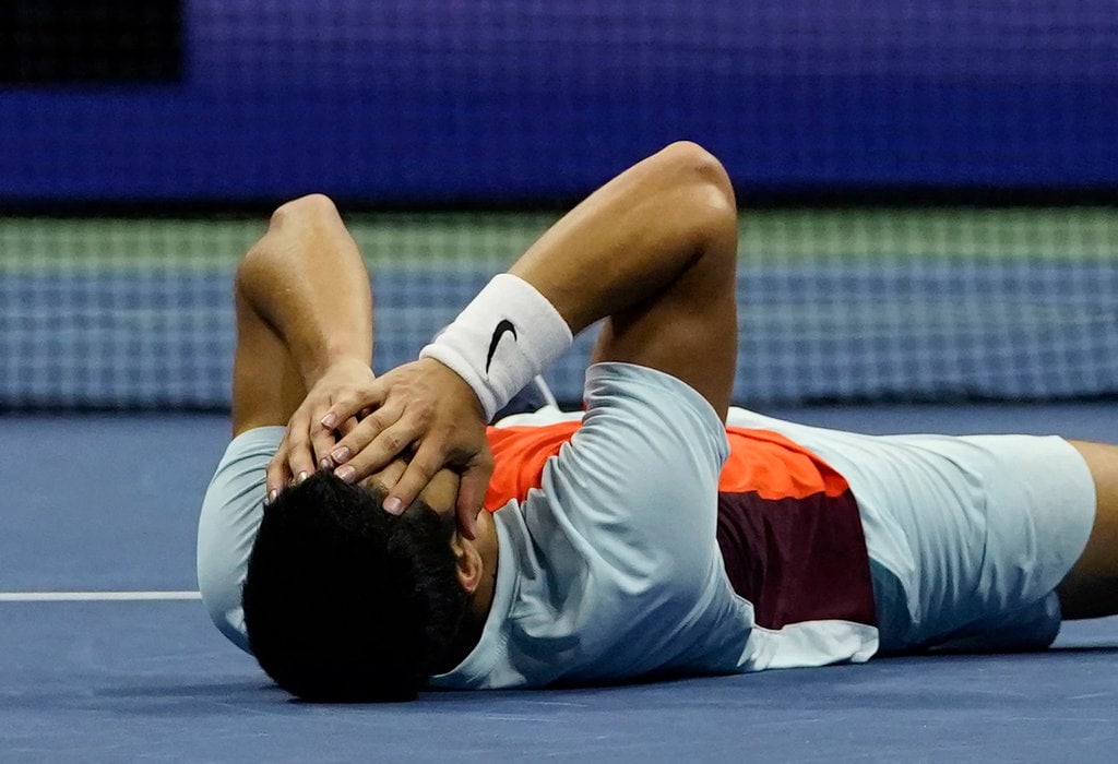 Carlos Alcaraz laying down on the court in disbelief after winning his first grand slam title