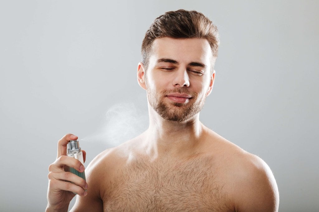 A man who's applying his cologne the right way.